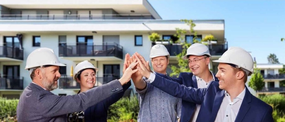 BAU-Symposium-Headerbild: Gruppe Bauleiter welche vor einem Gebäude abklatschen